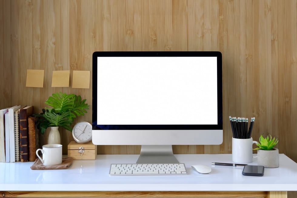 Workspace and blank screen desktop computer.Mockup desktop computer, coffee mug, plant and home office accessories on white desk.